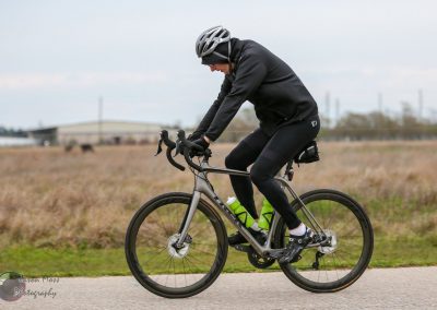 Efficient cyclist riding a Bike across an open field, showcasing Bluebonnet Express bike design.
