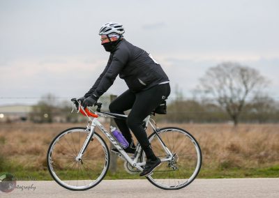 Bike rider in black cycling gear on a road, promoting Bluebonnet Express bike service.