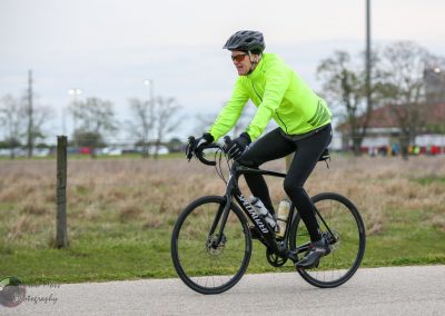 Vibrant cyclist riding a black Specialized bike on a paved trail during daytime.