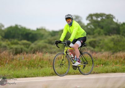 Helmeted cyclist riding a Focus bike on a scenic outdoor trail in green landscape.