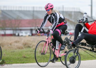 Cyclist riding a pink bike during Bluebonnet Express event on a paved trail.