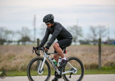 Rider on electric bike wearing helmet, cycling outdoors on paved path, EV biking adventure, Bluebonnet Express.