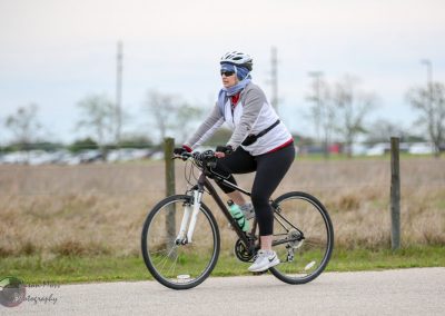 Comfortable woman riding a bike on a paved path in an open park area during daytime.