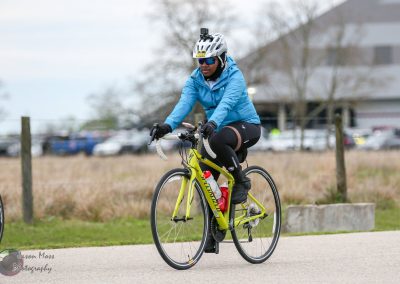 Bright yellow road bike for cycling and fitness, rider in blue jacket, black shorts, helmet, and sunglasses.