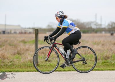 Smooth road cycling with a woman rider on a specialized bike in open rural landscape.