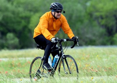 Vibrant cyclist riding mountain bike through green fields in outdoor adventure scene.