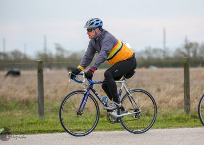 Vibrant cyclist wearing a colorful jacket on a scenic bike trail, promoting Bluebonnet Express bike events and cycling adventures.