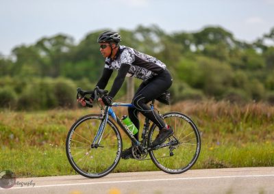 Cyclist riding a road bike in an outdoor landscape for Bluebonnet Express event SEO.