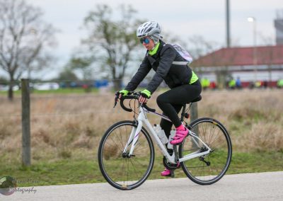 Bright female cyclist riding a road bike during daytime in outdoor setting.