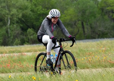 Bright woman cycling on trail in wildflower meadow, enjoying outdoor adventure.