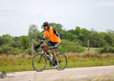 Velo cyclist riding on scenic countryside road, promoting outdoor biking and adventure.