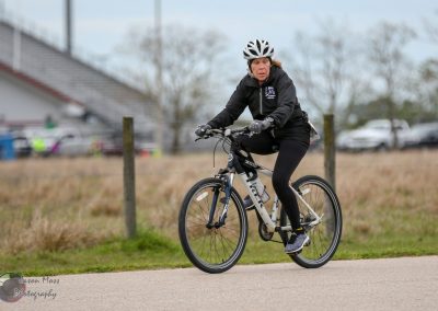 Comfortable woman riding Bluebonnet Express electric bike on scenic trail for eco-friendly transportation.