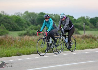 Bright women cyclists riding bikes on scenic outdoor trail in spring.