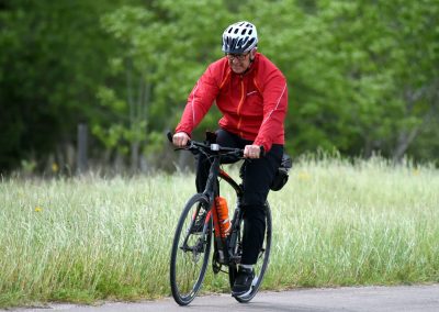 Vibrant male cyclist riding on trail surrounded by greenery, promoting outdoor biking adventure.