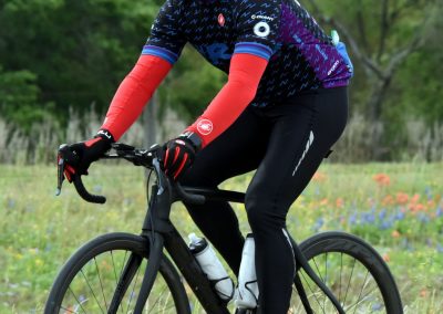 Vibrant cyclist in Bluebonnet Express gear riding on scenic trail, promoting eco-friendly transportation and outdoor activity.