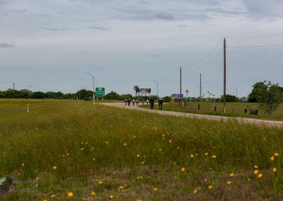 Cyclists riding on a rural highway in Texas, promoting Bluebonnet Express biking tours and scenic Texas routes.