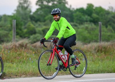 Bright green cycling jacket on a cyclist riding a red bike outdoors during daytime.