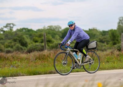 Vegan cyclist riding along scenic rural path with lush greenery, promoting healthy lifestyle and eco-friendly transportation.