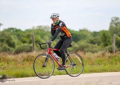 Vegan cyclist riding on scenic countryside road, promoting eco-friendly biking, Bluebonnet Express cycling event.