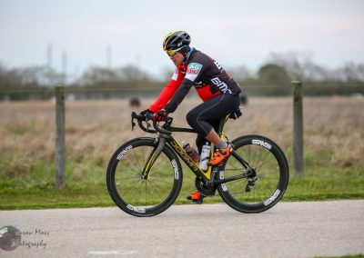 A cyclist riding a Black and Yellow road bike outdoors, practicing eco-friendly travel in scenic countryside.