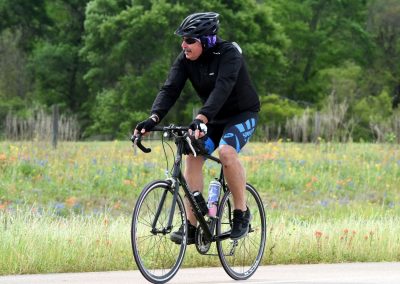 Lightweight road bike rider on a scenic trail with wildflowers in the background.