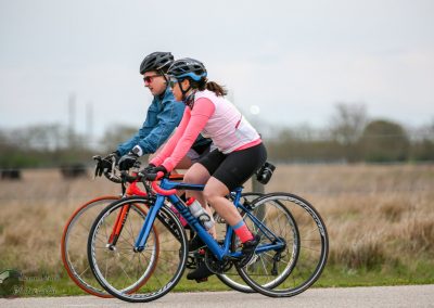 Brightly colored cyclists riding on a scenic trail during daytime.