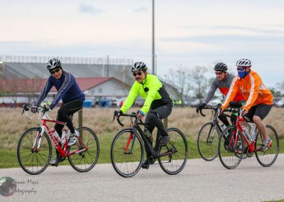 Bright neon cyclists group riding on dedicated bike trail during daytime.