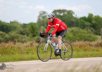 Bright cyclist riding on scenic rural road, promoting Bluebonnet Express bike tour.