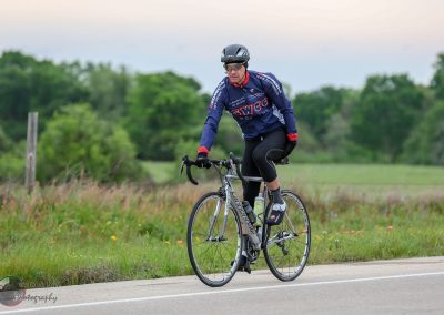 Velo cyclist riding on scenic countryside road, promoting Bluebonnet Express bike service.