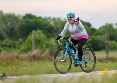 Bright woman cyclist enjoying a scenic ride on Bluebonnet Express bike trail, promoting healthy outdoor biking activities.