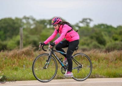 Bright pink cycling jacket and helmet on female cyclist riding a bike outdoors, promoting Bluebonnet Express.