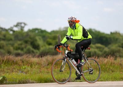 Vibrant cyclist in neon jacket riding on scenic countryside road during daytime.