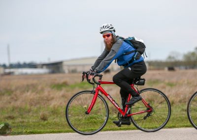 Vibrant red bicycle rider apparel, outdoor cycling adventure, scenic trail, professional cycling gear, fitness, outdoor recreation.