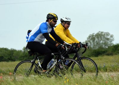 Vibrant tandem cycling on nature trail in Bluebonnet landscape, ideal for outdoor fitness and adventure.