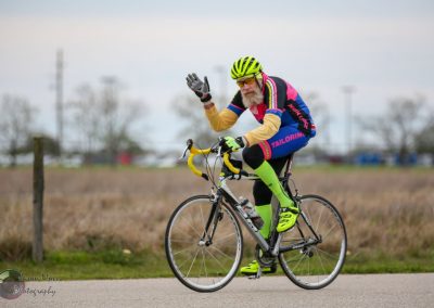 Vibrant cyclist in colorful gear riding on a paved path, promoting Bluebonnet Express bike service and cycling enthusiast lifestyle.