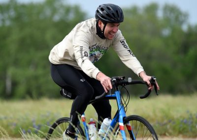 Bright cyclist riding a Bluebonnet Express bike outdoors during daytime.