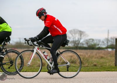 Bike rider in red bike jersey with "Ride Marshal" text during outdoor cycling event.