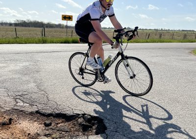 Bright male cyclist riding a mountain bike on rural road, summer outdoor activity, Bluebonnet Express.