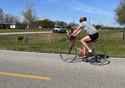 High-performance cyclist riding a red road bike outdoors during daytime.