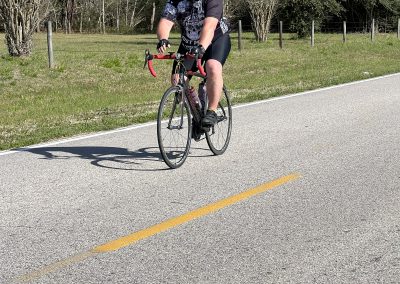 Rider on scenic road wearing bike gear, promoting Bluebonnet Express cycling tour.