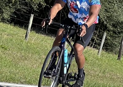Brightly colored cyclist riding a bike with "Bluebonnet Express" branding, enjoying a sunny day on a scenic route.