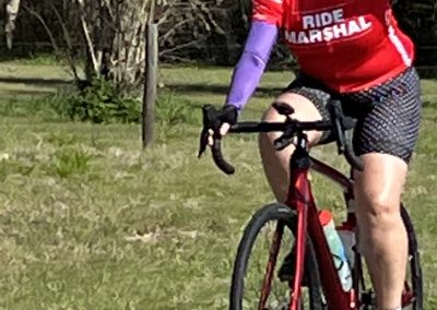 Vibrant cyclist riding a red bike on scenic trail, promoting Bluebonnet Express cycling event.