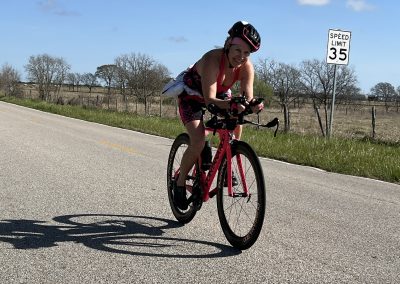 Bright woman riding a pink road bicycle on a rural road, enjoying cycling outdoors.