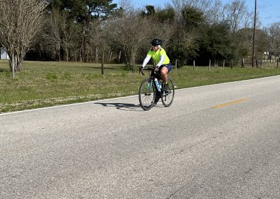 Bike riding along scenic rural road in daylight, promoting Bluebonnet Express cycling services.