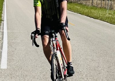 1. Man riding a road bike on a rural road, wearing a helmet and cycling gear.