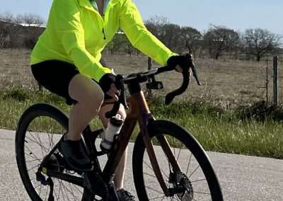 Bright yellow cycling jacket on enthusiastic rider on road, enjoying outdoor biking adventure.