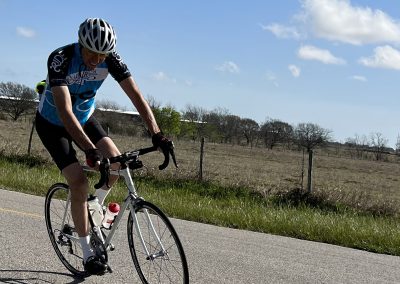 Vibrant cyclist riding on scenic rural road in Bluebonnet country during sunny day.
