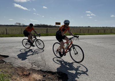 Kids cycling on a rural road with blue sky and clouds, promoting Bluebonnet Express outdoor bike adventures.