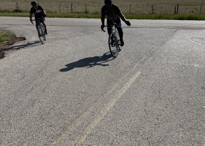 Bicycle riders on scenic rural road under blue sky, promoting Bluebonnet Express bike tours.