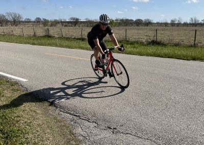 Velo cyclist riding on road, enjoying scenic Texas countryside, Bluebonnet Express cycling adventure.